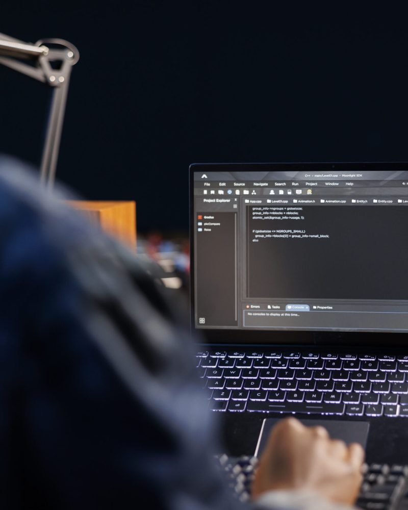 African American developer managing a system, typing on keyboard and laptop screen showing software programming. Professional freelancer working on data center and network security.